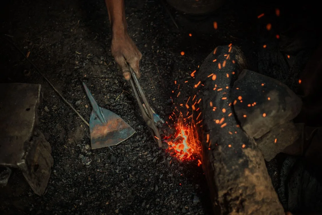 A blacksmith hammering hot metal with sparks flying, like forging gear in how to get netherite in minecraft
